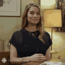 a woman sitting at a table with the word schitts creek written on the bottom