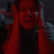 a woman is screaming in a dark room with headphones on .