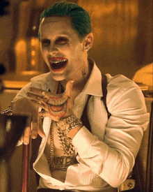a man with green hair is wearing a white shirt and bracelets