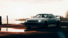 a white sports car is parked in a puddle near the water