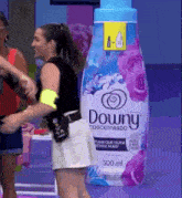 a woman is standing in front of a giant downy bottle