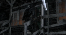 a man in a mask is walking up the stairs of a cabin .