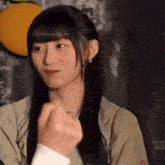 a young woman with long black hair is making a heart shape with her hand .