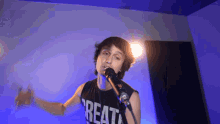 a young man singing into a microphone wearing a black shirt that says great