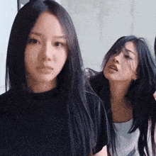 a woman with long black hair is standing next to another woman with shorter hair