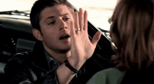 a man is giving a woman a high five in a car .