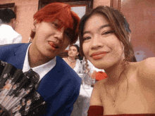 a man with red hair and a woman in a red dress pose for a picture