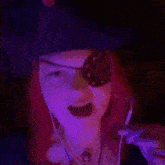 a woman with red hair is wearing a pirate hat and eye patch while listening to music .