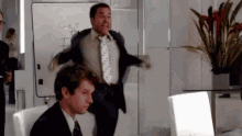 a man in a suit and tie is dancing in front of a white board with the word get written on it