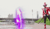 a red and black superhero is holding a purple sword and standing next to a green superhero .