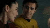 a man and a woman are looking at each other and the man is wearing a yellow uniform