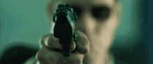 a man is pointing a gun at the camera while wearing sunglasses .
