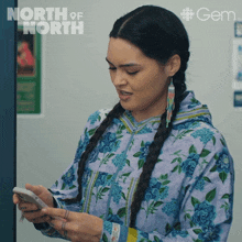 a woman in a floral jacket is looking at her phone with a north of north logo in the background