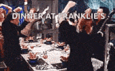 a group of people are standing around a table with the words `` dinner at franklie 's '' written on the bottom .