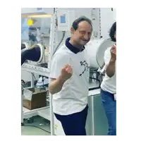 a man in a white shirt is standing in front of a machine with his fist in the air .