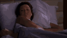 a woman sleeping in a bed with white sheets and pillows