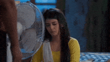 a woman is sitting in front of a fan in a bedroom .