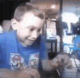a young boy wearing a blue shirt with the letter m on the front