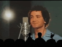 a man singing into a microphone with a crowd watching