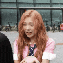 a girl with red hair is wearing a pink shirt and a blue tie