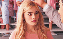 a woman in a pink shirt is being touched by a man .