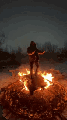 a man in a hooded jacket stands on a pile of fire