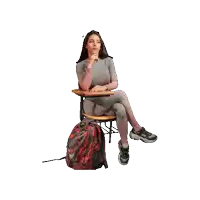 a woman is sitting at a desk with her legs crossed and a backpack next to her .