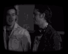 two men are standing next to each other in a dark room