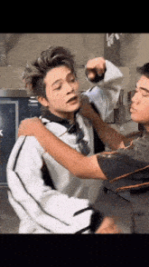 a man is holding another man 's arm while they are standing next to each other in a room .