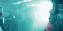 a woman is dancing on a pole in a dark room .