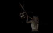 a woman is standing in the dark holding a stick .