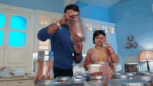a man and a woman are standing in a kitchen with jars of spices