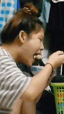 a woman in a striped shirt is eating something with a spoon