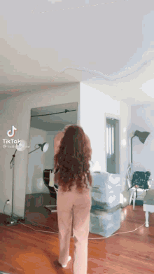a woman with long red hair is standing in a living room with boxes on the floor ..