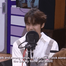 a young man is sitting in front of a microphone and saying i wanted to pick some like say my name and wave