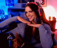 a woman wearing headphones and a blue sweater is smiling in front of a shure microphone