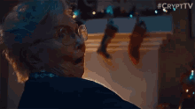 an older woman with glasses is screaming in front of christmas stockings hanging on a mantle ..