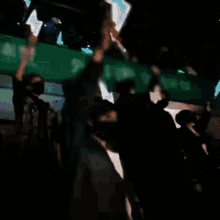 a blurry photo of people holding up a green banner that says ' a ' on it