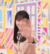 a girl is waving her hand in front of a colorful wall .
