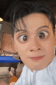 a man is making a funny face while sitting at a table with a pool table in the background .