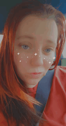 a woman with red hair is wearing a red shirt and a seat belt