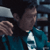 a man in a green jacket with the word netflix on the bottom right