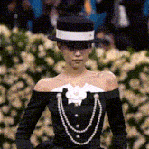 a woman wearing a hat and a necklace with pearls
