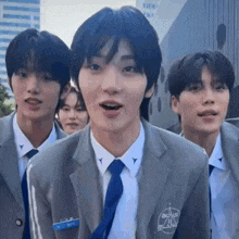 a group of young men wearing suits and ties are standing next to each other and looking at the camera .