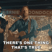a man playing a guitar with the words there 's one thing that 's true behind him