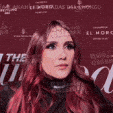 a woman with red hair stands in front of a sign that says el moro