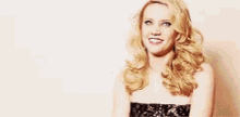 a woman in a strapless black dress is smiling .