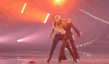 a woman in a red dress is dancing with a man in a silver outfit