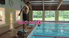 a man is jumping into a swimming pool with the word microsoft in the background