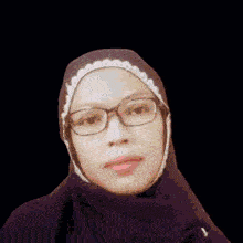 a woman wearing glasses and a hijab is standing in front of a heart with the words `` thank you '' .